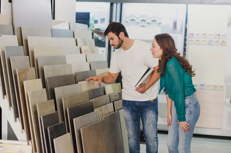 Homme et femme dans showroom carrelage examinent échantillons de carreaux muraux et sol
