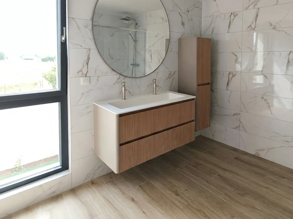 Salle de bain moderne avec meuble vasque double suspendu en bois et blanc mat, deux robinets colonne en inox brossé, miroir rond, colonne de rangement assortie