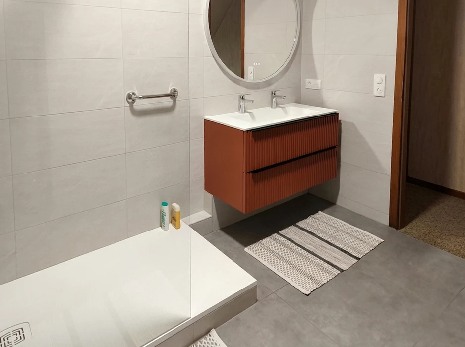 Salle de bain moderne avec meuble vasque double suspendu en bois teinté terracotta à façades striées, plan vasque blanc intégré, robinetterie chromée