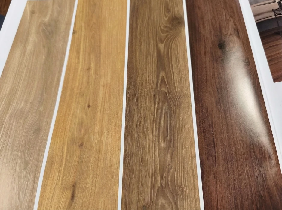 Échantillons de planchers stratifiés ou vinyle LVT disposés en éventail sur carrelage gris anthracite