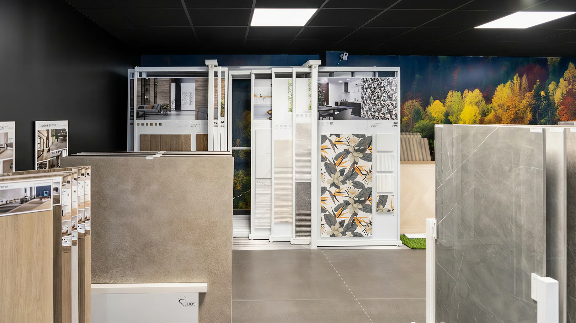 Photographie professionnelle du showroom de 500 m² du Square L'Agencement Autrement montrant un espace d'exposition haut de gamme et moderne. La scène capture l'intérieur d'un showroom privatif présentant des cuisines aménagées sur mesure avec matériaux premium, des dressings sophistiqués, des salles de bain design, et des présentoirs de carrelage exclusif italien et espagnol. L'ambiance est lumineuse et épurée, avec un mobilier de prestige, des revêtements de sol en PVC et stratifié haut de gamme visibles. Le design intérieur transmet l'exclusivité, le professionnalisme et l'accessibilité sur rendez-vous. L'accent est mis sur la qualité des matériaux, l'agencement personnalisé et l'atmosphère premium du concept retail.