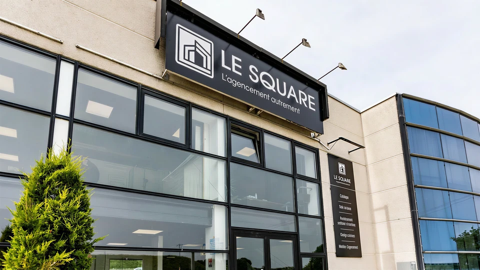 Int&eacute;rieur moderne d'un showroom de luxe&nbsp;: espace lumineux et &eacute;pur&eacute; de 500 m&sup2; avec exposition de cuisines haut de gamme, dressings sur mesure, carrelages italiens et espagnols, rev&ecirc;tements de sol premium et meubles de salle de bain design. L'ambiance est claire et professionnelle, avec des mat&eacute;riaux de qualit&eacute; visibles, une mise en sc&egrave;ne soign&eacute;e, et un d&eacute;tail subtil montrant deux personnes en conversation (client et sp&eacute;cialiste) qui explore les mat&eacute;riaux c&ocirc;te &agrave; c&ocirc;te, illustrant le conseil personnalis&eacute; dans un environnement privatis&eacute; et tranquille.