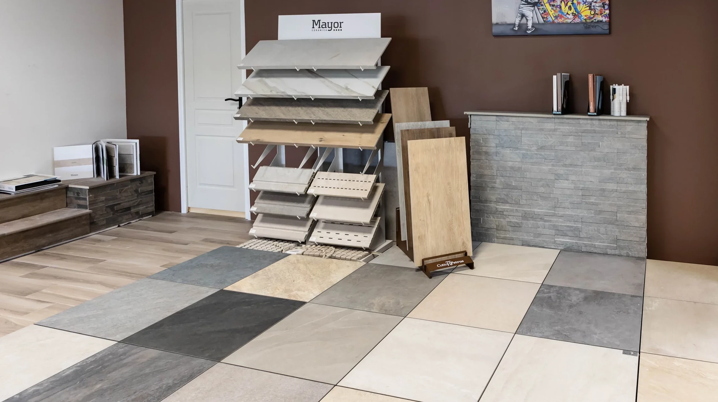 Showroom intérieur de revêtements avec présentoirs muraux et au sol exposant diverses gammes de carrelages, pierres naturelles et matériaux de construction